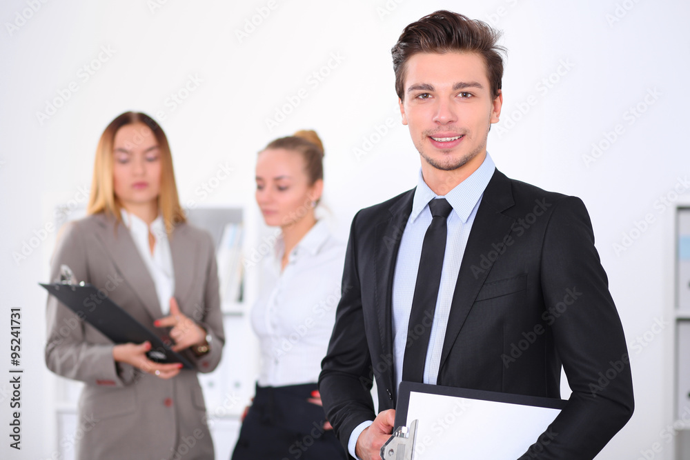 Cheerful business man in office with colleagues in the background, sturt  up team