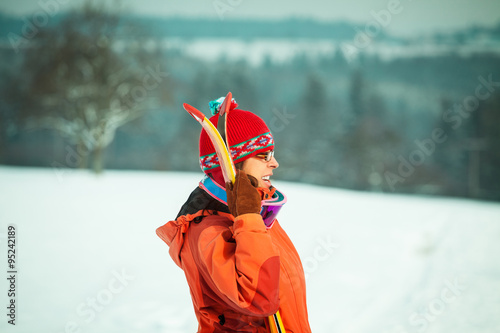 Close up portrait of mid adult woman wearing orange jacket holding skis