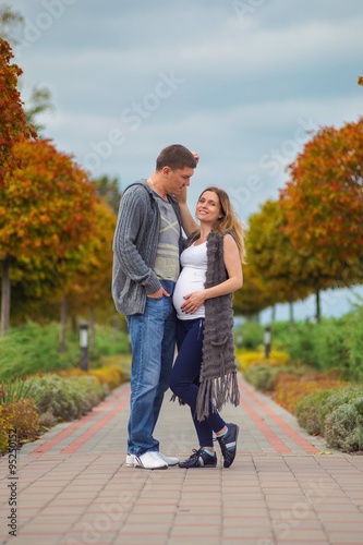 Pregnant couple - walking at the autumn park