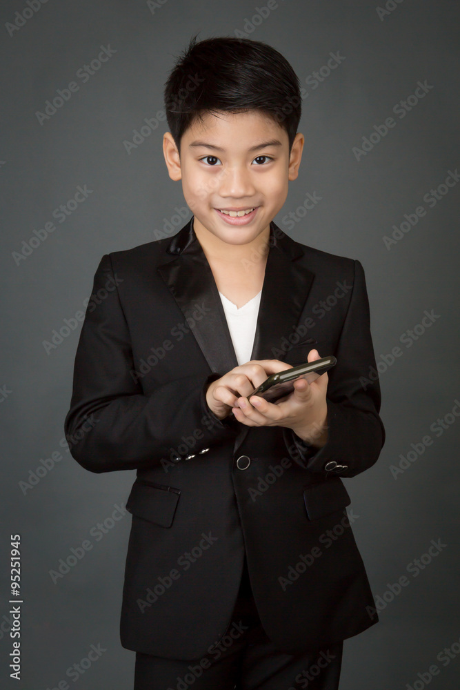 Happy asian child in black suit holding digital cell phone Happy asian child in black suit holding digital cell phone