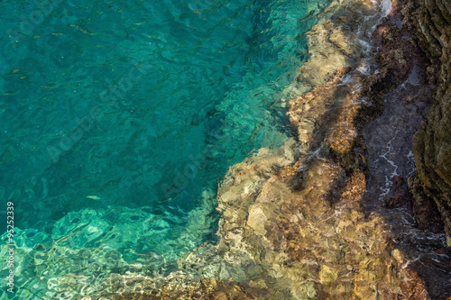 Rocky seabed under water. Gradient color from turquoise seawater to light brown rock. Photo was taken parallel to the horizon. 