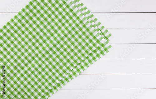 Green towel over white wooden kitchen table. View from above with copy space