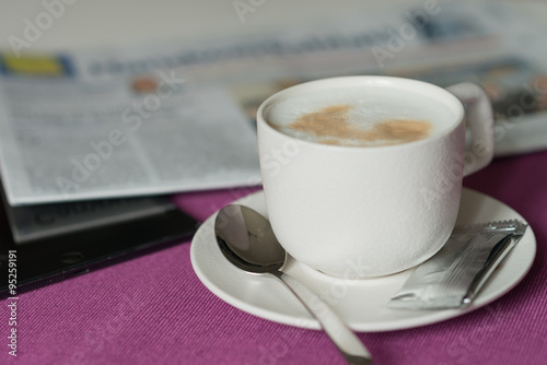 morning coffee with milk foam , newspaper, tablet