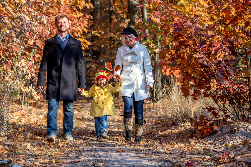 Two Generation Family Walking in Colorful Autumnal Forest Alley Smiling Father Mother Holding Hands of Little Baby Girl Bright Casual Clothing Front View