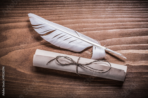 Rolled aged paper quill on wooden board horizontal version