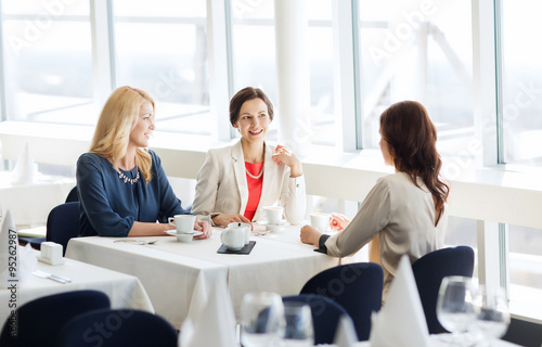 women drinking coffee and talking at restaurant