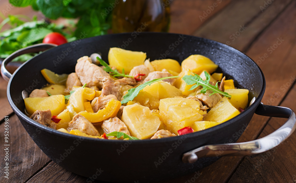 Stewed potatoes with meat and vegetables in a roasting tin on a wooden background Stewed potatoes with meat and vegetables in a roasting tin on a wooden background