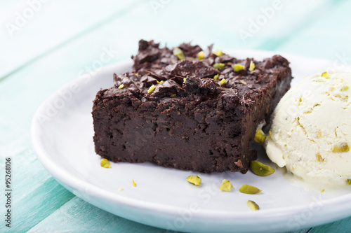 Chocolate brownie, cake, white plate on a turquoise wooden background