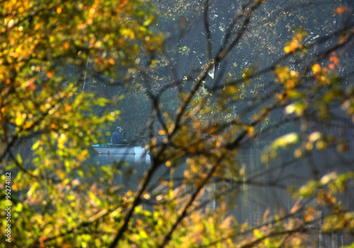 view through the autumn trees on man i boat fishing