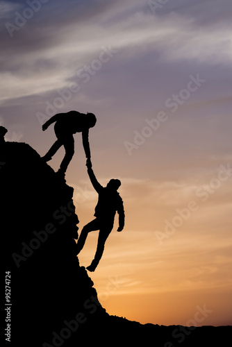 Silhouette of helping hand between two climber