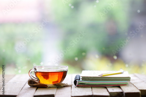 tea in glass and notebook with pencil at windows