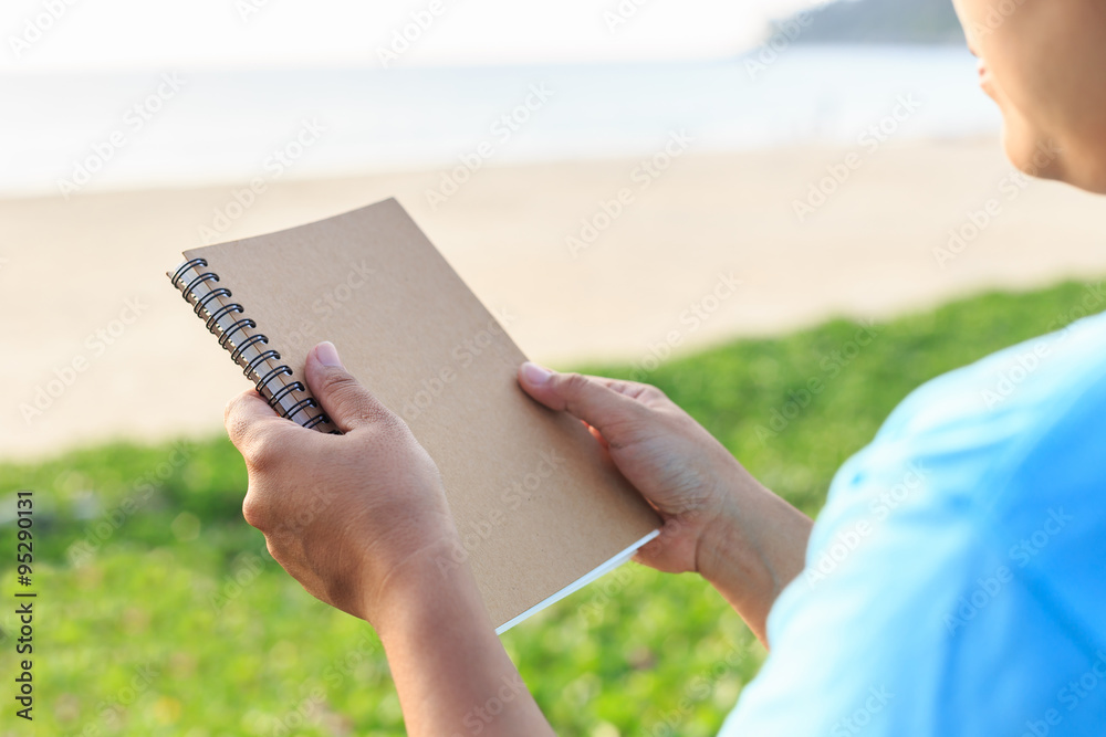 Asian woman holding notebook on the beach