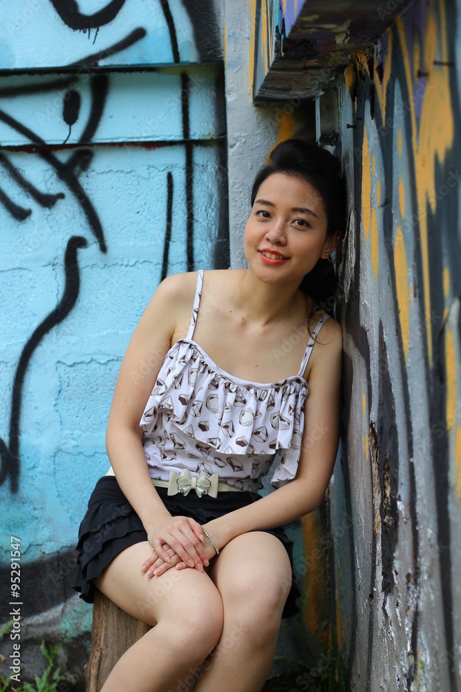 Naklejka premium Portrait of thai adult beautiful girl relax and smile on graffiti wall 