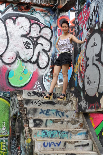 Portrait of thai adult beautiful girl relax and smile on graffiti wall 