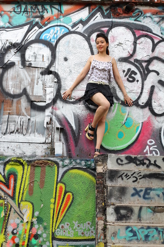 Portrait of thai adult beautiful girl relax and smile on graffiti wall
