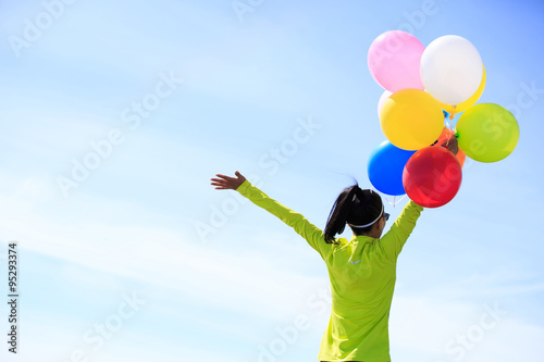 cheering young woman  on mountain peak with colorful balloons © lzf