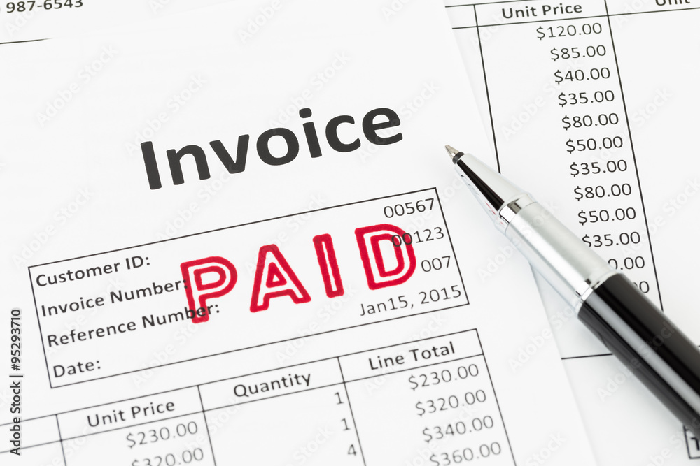 Fototapeta premium Invoice and pen with paid stamp; invoice is mock-up