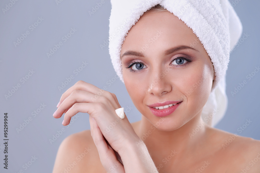 Young woman putting cream on her hand Isolated on gray background Young woman putting cream on her hand Isolated on gray background