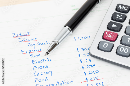 Hand writing home budget with calculator