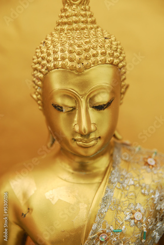 Gold Buddha close up portrait plastic wrap in yellow background © koonkhunstock