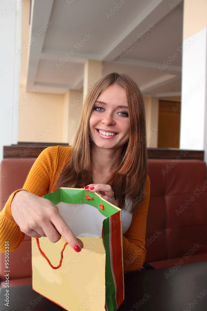 Young smile girl shows purchase in shopping bag Young smile girl shows purchase in shopping bag