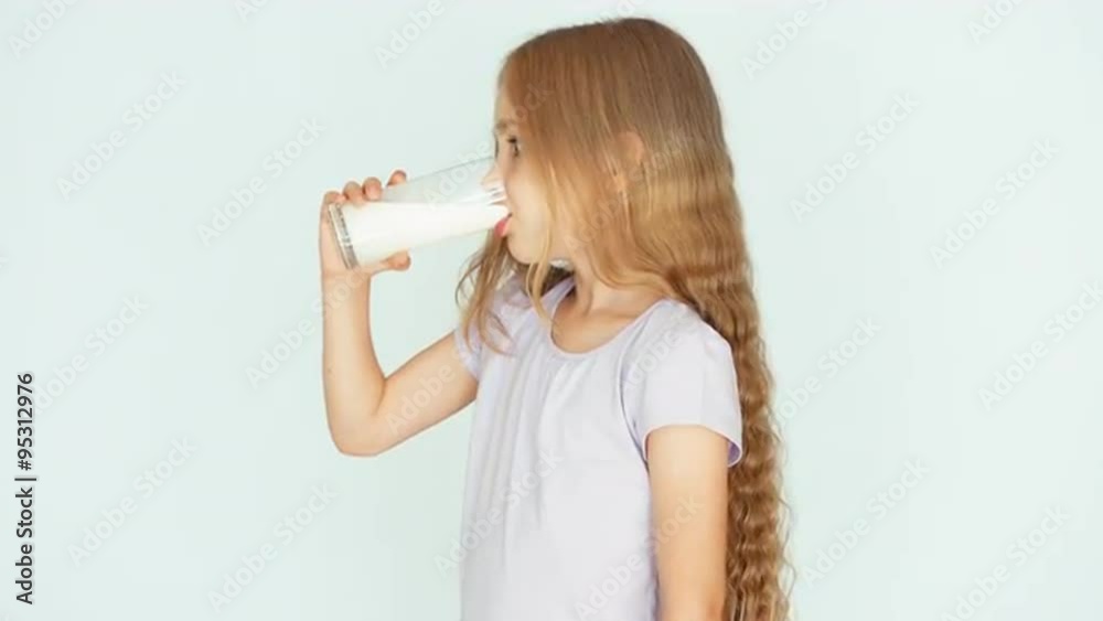 Child drinking milk. Milk mustache. Girl with beautiful blond hair on a white background. Thumb up. Ok