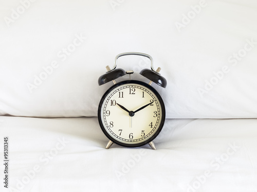 Alarm clock on white bed