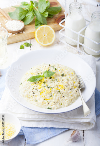 Risotto with lemon and fresh basil. White wooden background