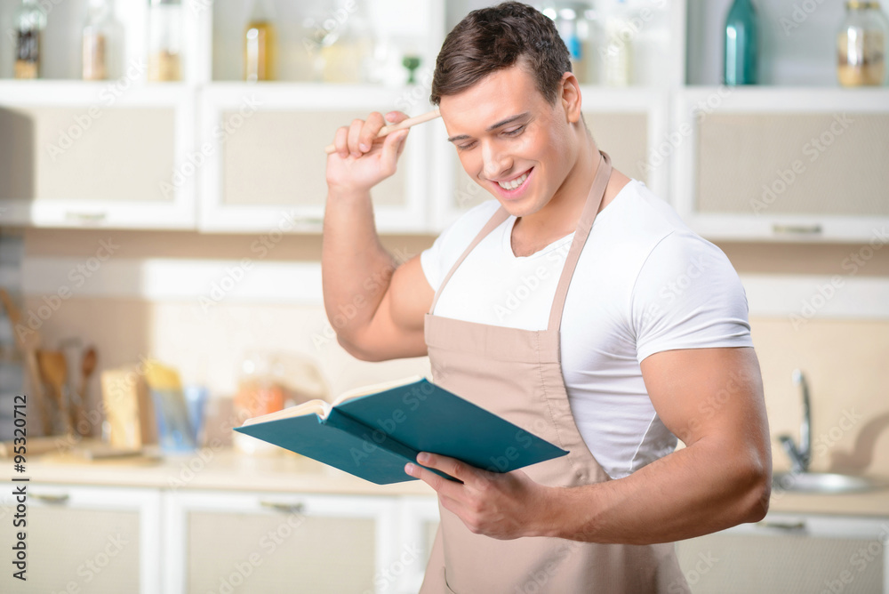 Young smiling cook is reading a cookbook. Young smiling cook is reading a cookbook.