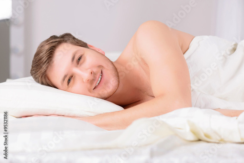 Young man in bed lying on the side.