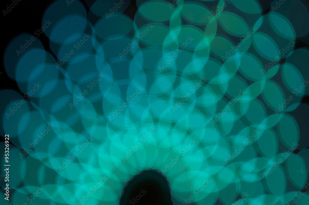 Defocused turquoise circles at night. Bokeh background.