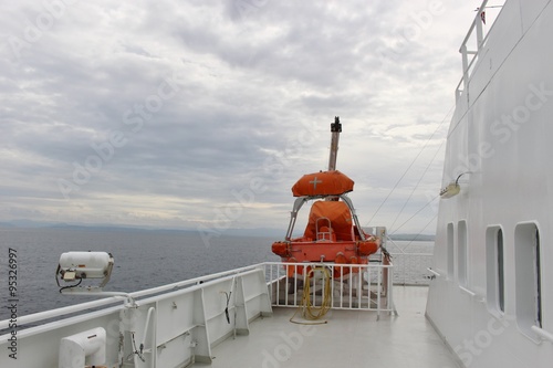 Lifeboat on the deck of a ferry in Norway, Europe. The ship is passing the Fjord Boknafjorden. photo