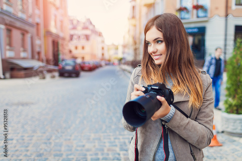 Happy woman on vacation photographing with camera on the city street © A.Kazak