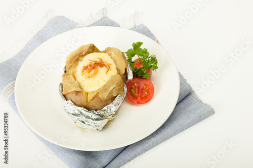 Baked potato with cheese in foliage with fresh tomato
