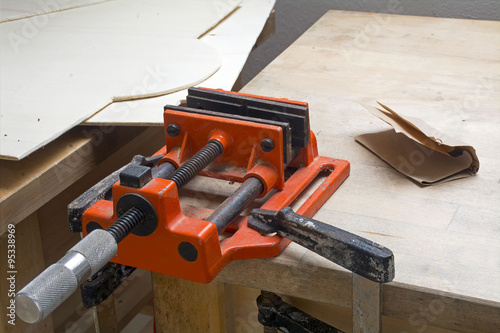 old table vise in orange with dust and rust on a home workbench
