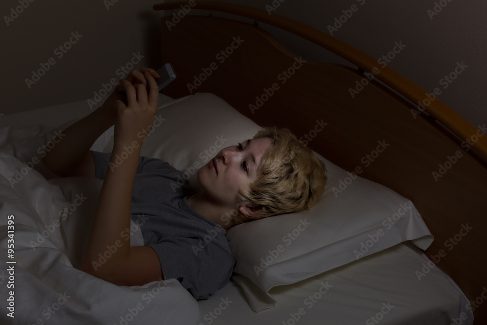 Teen girl texting late at night while in bed Teen girl texting late at night while in bed