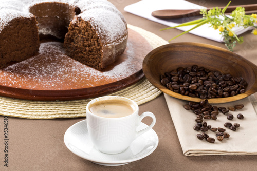 Chocolate cake on the table with cooffe in the background.