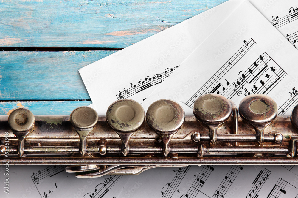 Obraz premium Old flute with sheet music on blue wooden boards