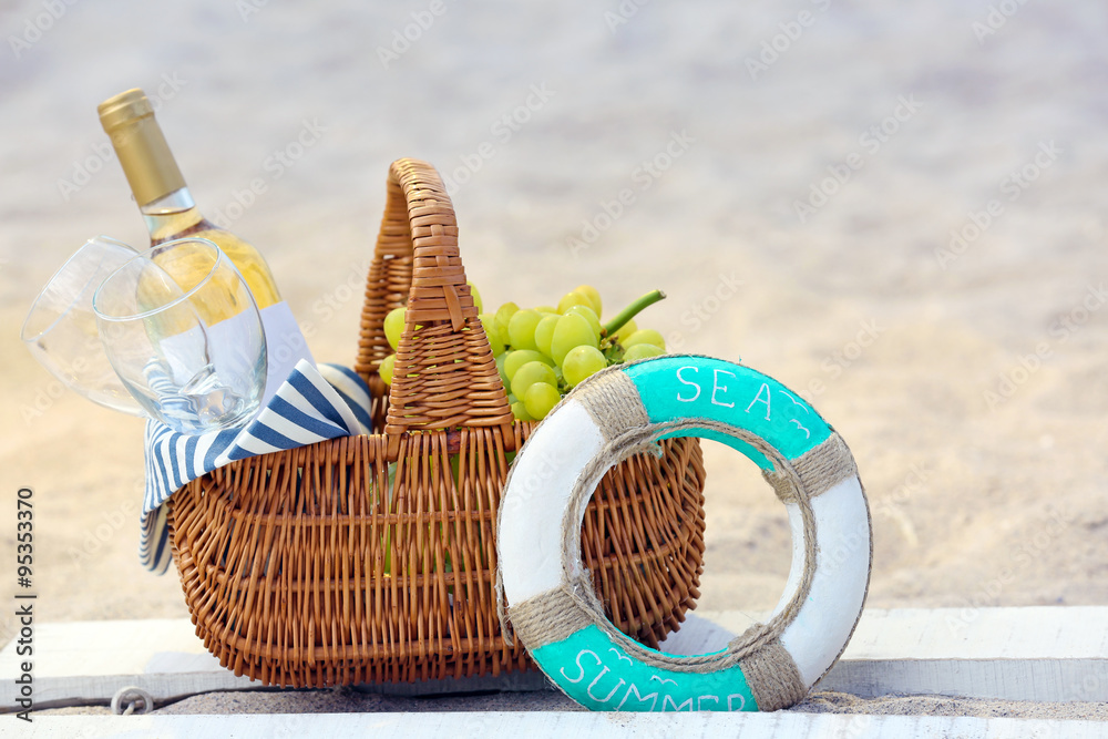 Fototapeta premium Picnic basket with bottle of wine on sand beach