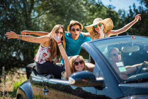 young people having fun in a black convertible by a sunny day © jackfrog