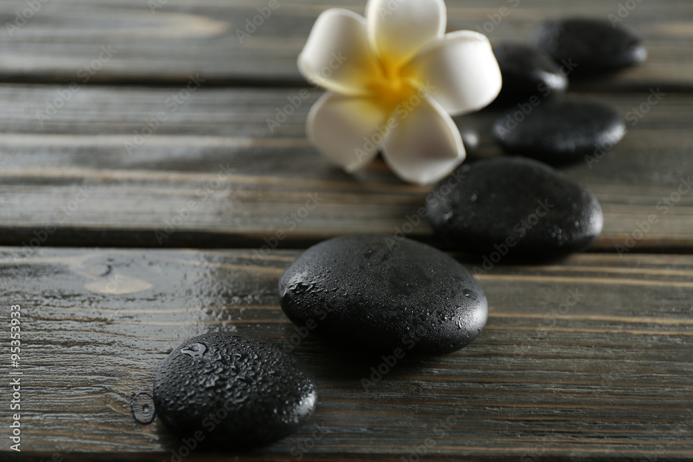 White plumeria flower with pebbles on wooden background White plumeria flower with pebbles on wooden background
