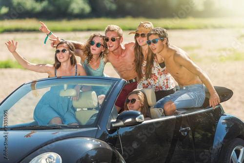 young people are having fun in a black convertible at the beach © jackfrog