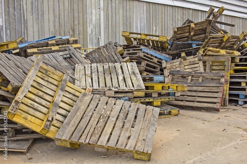 Old Stacked wooden pallets are lumber near a factory.
dilapidated wood pallets background.