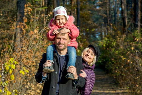 Happy Family on the Walk in Autumnal Forest Father Mother Little Baby Daughter Together on Weekend Walk on Autumnal Colors Forest Sunny Day Smiling Faces Child Sitting on Daddy Shoulders