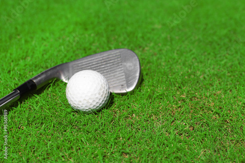 Golf club and ball on a green grass