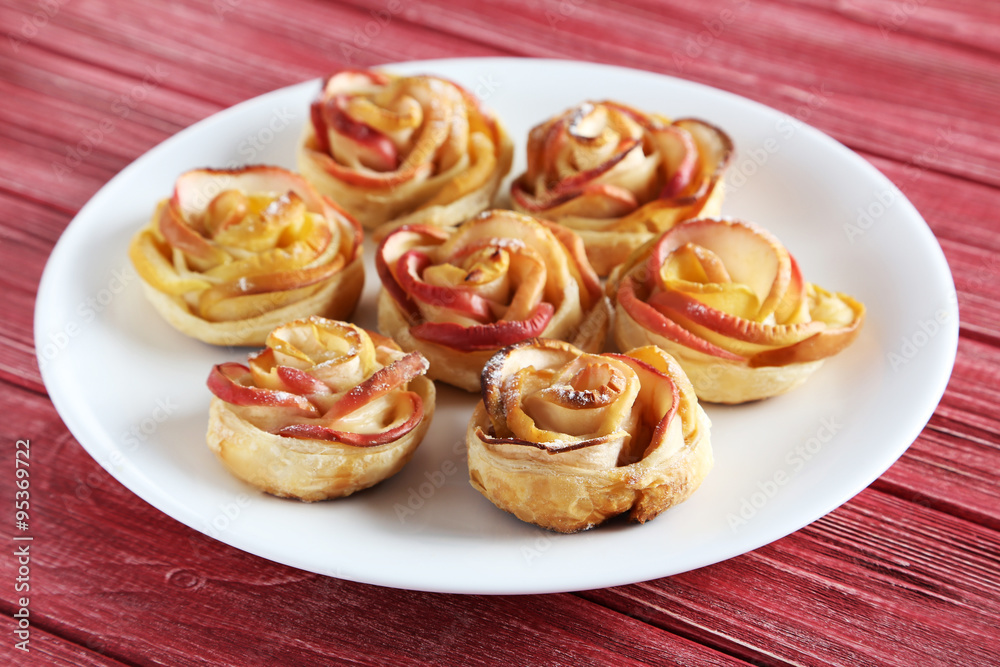 Fresh puff pastry with apple shaped roses on red wooden table