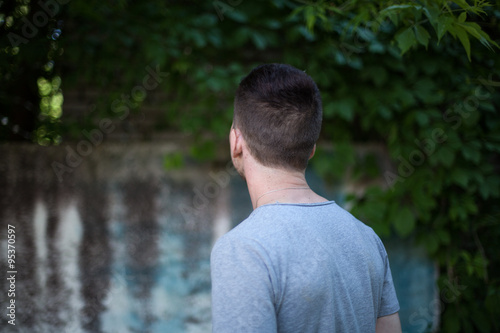 portrait of a man against the background of the wall with greens © zdyma4