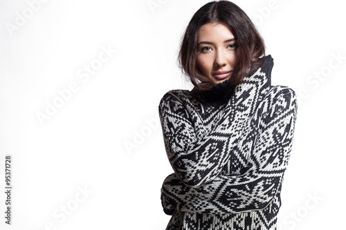 Young woman in a sweater with snowflakes is posing in studio
