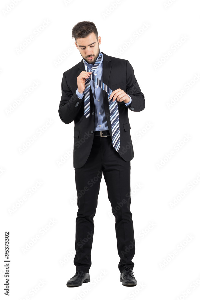 Obraz premium Young bearded business man getting dressed. Full body length portrait isolated over white studio background. 