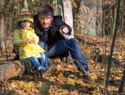 European Family Father and Little Baby Girl sitting in Autumnal Forest Pointing on something Watching and Looking